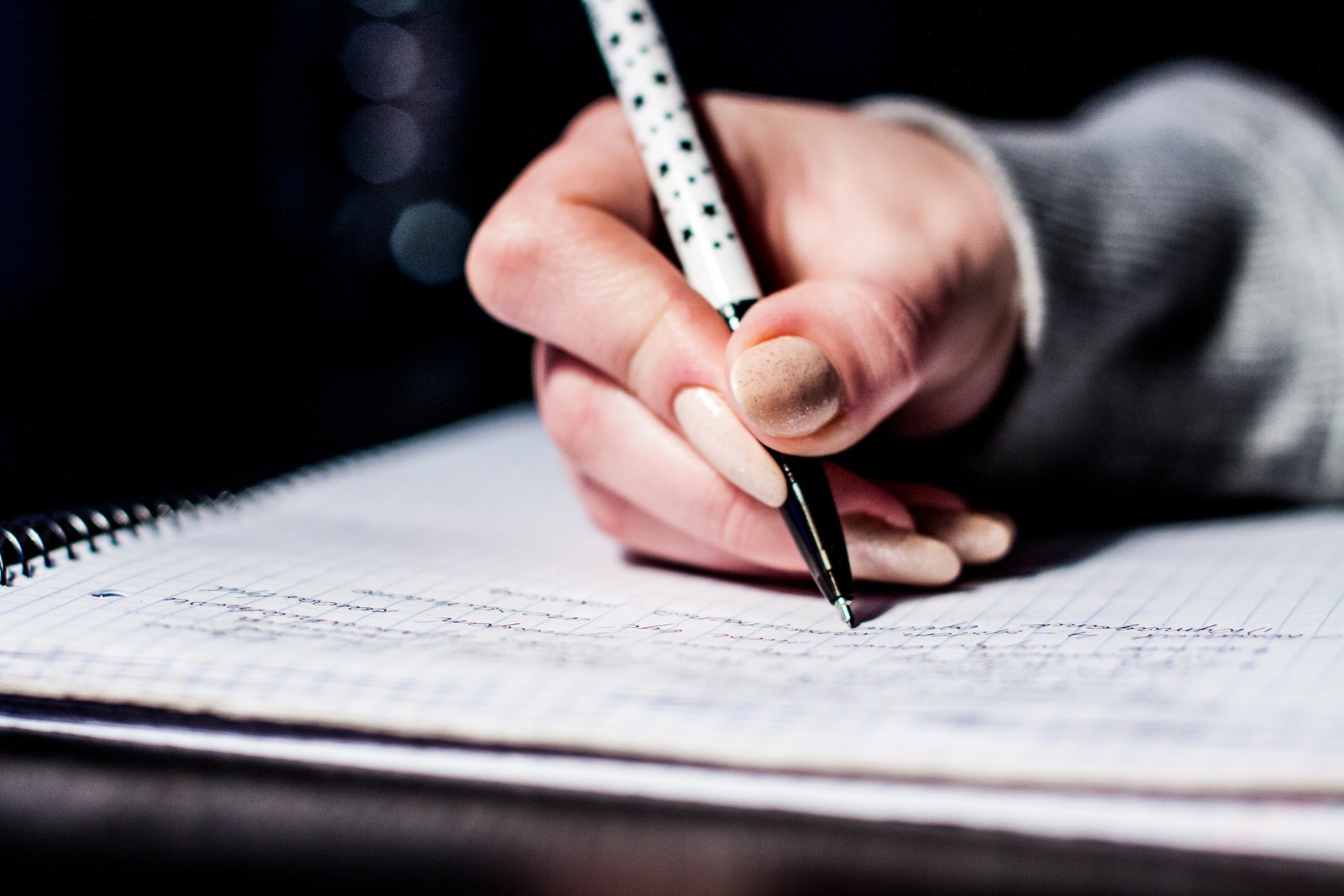 Una mano escribe con un bolígrafo en un cuaderno.