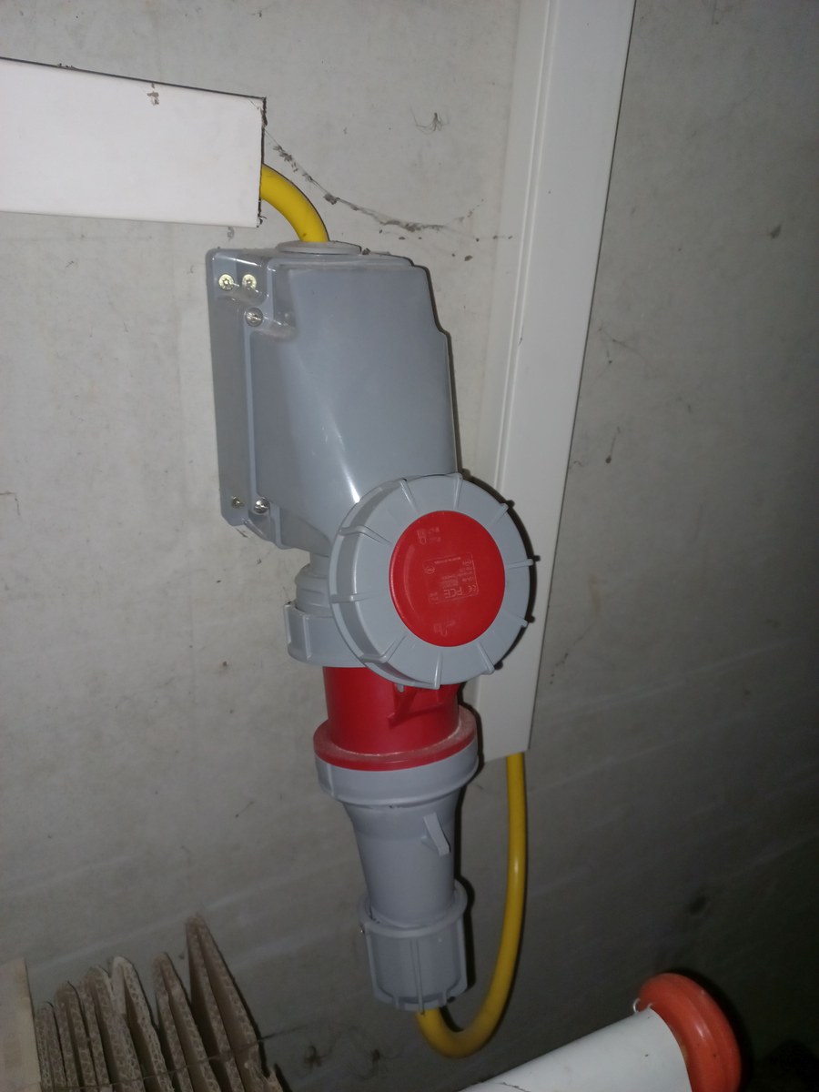 Conectores industriales rojos y cable en una pared de un espacio de trabajo.